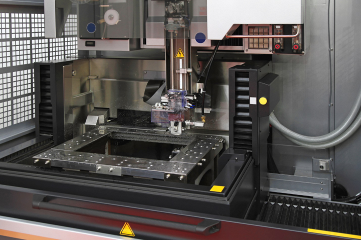 6 axis industrial robot loading a graphite electrode into a sinker EDM machine from a palletized magazine storage system